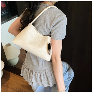 Detail of cream woven shoulder bag texture with delicate strap and brand tag