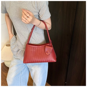 Detail of a deep red woven leather shoulder bag showing the premium textured surface
