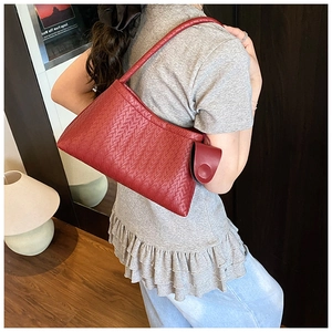 Detail of red woven leather underarm bag with a round mini pouch and a slim strap