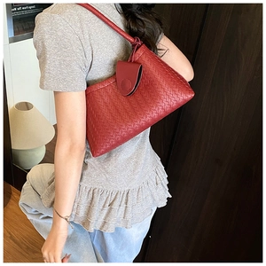 Detail of red woven leather shoulder bag with intricate intrecciato texture and magnetic clasp