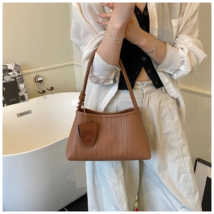 Detail of caramel brown woven leather underarm bag with decorative round pouch
