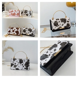 Detail view of cow print handbags with metallic handles and elegant gold chain straps