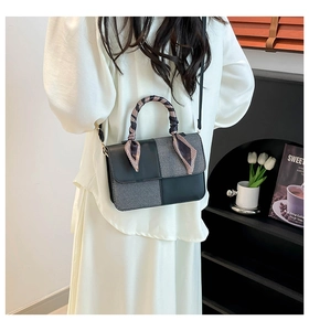 Detail of color-block handbag featuring a silk scarf wrapped handle and fine leather texture