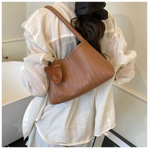 Detailed view of brown woven leather texture on a stylish minimalist hobo underarm bag