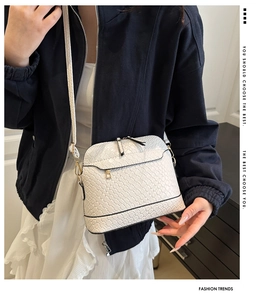 Detail of white woven texture shell bag with gold metal hardware and slim shoulder strap