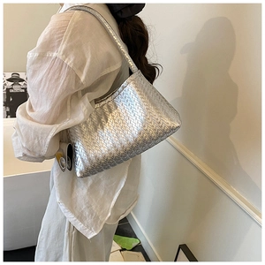 Detailed view of silver woven leather shoulder bag texture on a model's arm