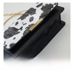Detailed view of the cow print texture and premium stitching on the mini square bag