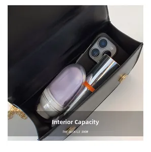 Internal capacity of black crossbody bag showing smartphone and makeup storage
