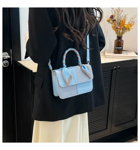Close-up of light blue crossbody bag with woven texture and decorative silk scarf handle
