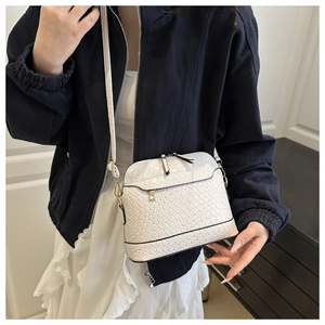 White woven shell bag with gold zipper detail worn by model in minimalist fashion style