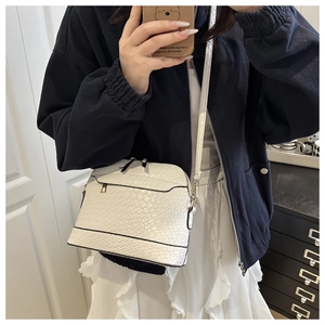 Detail of white woven texture crossbody bag with gold hardware shown on female model