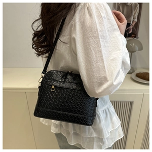 Detail of black woven texture shell bag with gold double zippers worn by a model