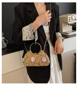 Model wearing sequined floral evening clutch with gold ring handle and chain strap
