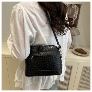 Detail of black woven texture shoulder bag with gold zipper and adjustable buckle strap