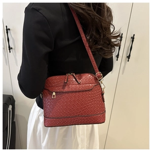 Detail of deep red woven texture shell bag with golden zipper and hardware accents