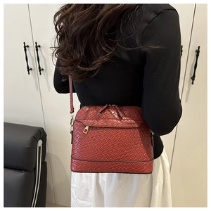 Detailed close-up of wine red woven leather shell bag worn by model over white skirt