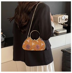 Detail of sequin floral evening bag with gold ring handle and chain on a black suit