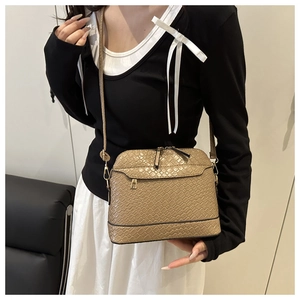 Close-up of khaki shell crossbody bag featuring woven texture and gold zipper detail