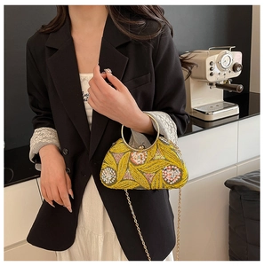 Detail of yellow sequin evening bag with floral embroidery and golden metal handle