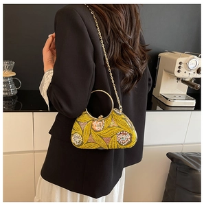 Detail of yellow sequin evening bag with floral embroidery and gold metal handle