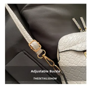 Close-up of white crocodile embossed leather bag with adjustable golden metal buckles