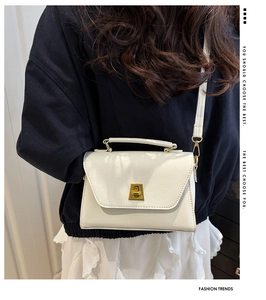 Rear view of a model wearing a white pebbled leather crossbody bag with gold twist lock