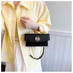 Detailed shot of black woven texture bag featuring gold M logo and ring handle