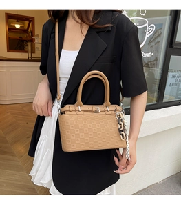 Detail of khaki embossed checkered handbag with buckle strap and chic chain pendant