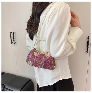 Model showcasing a sequined floral evening bag with a gold ring handle and chain strap