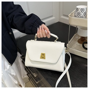 Detail of white lychee pattern leather bag featuring a vintage gold metal lock and handle
