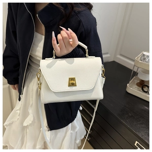 Detail of white lychee texture crossbody bag featuring a golden trapezoid twist lock