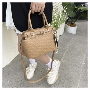 Detail of khaki tote bag featuring square embossed texture and decorative silk scarf