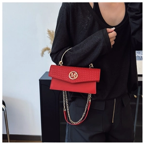 Detailed view of red woven flap handbag with golden M logo and chain strap on a model