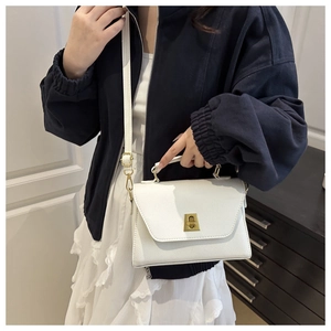 Close-up of white lychee texture leather bag with elegant gold metal twist lock detail