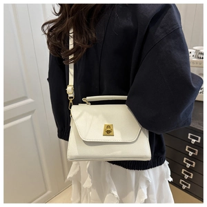 Detailed view of white lychee leather texture and vintage gold twist lock on handbag