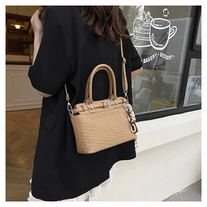 Detail of khaki embossed tote bag with geometric texture and decorative chain strap