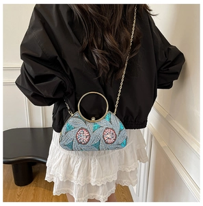 Detail of blue sequined evening bag with floral embroidery and golden round handle