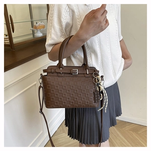 Detail of dark brown litchi grain leather tote with square embossing and metal buckle