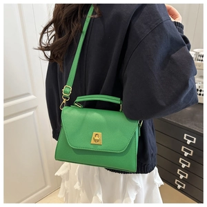 Detail of bright green pebble leather handbag with gold twist lock and crossbody strap