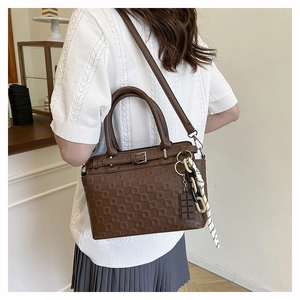 Detail of dark brown leather tote bag with embossed checkerboard pattern and charms