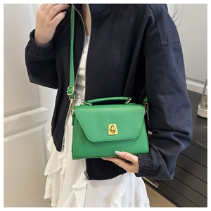 Detailed shot of green textured crossbody bag with golden twist-lock on a model