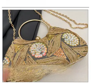 Close-up of golden evening bag with floral sequins, embroidery and metal ring handle