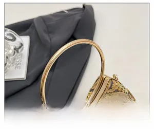 Detail of luxury evening clutch featuring golden floral embroidery and metallic ring handle