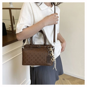 Brown checkerboard tote bag shown on model with creative charms and adjustable strap