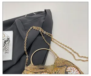 Close-up of golden sequins and floral embroidery on evening clutch with ring handle