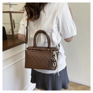 Close-up of brown tote bag featuring textured square embossing and chocolate charm detail