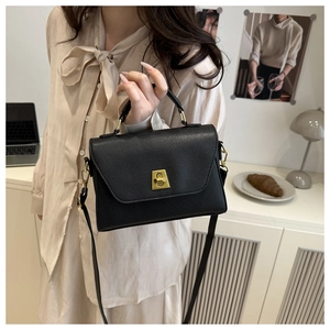 Detail of a black pebbled leather crossbody bag with a gold twist lock and handle hardware