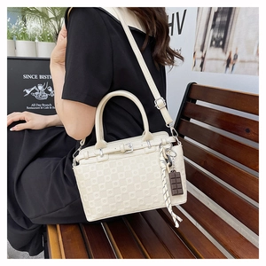 Detail of cream white leather tote bag with checkerboard embossing and chocolate charm