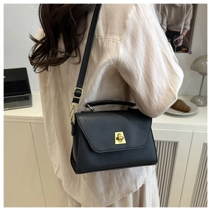 Detail of black lychee leather crossbody bag with golden metal buckle and adjustable strap