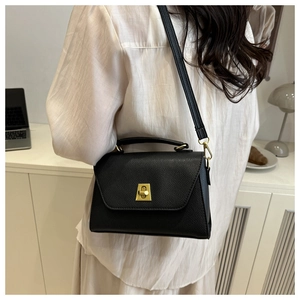 Close-up of black lychee grain leather crossbody bag with elegant gold metal twist lock